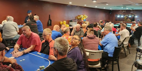 Group playing poker in a room with blue tables.
