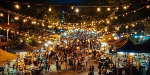 Busy night market with string lights and crowds.