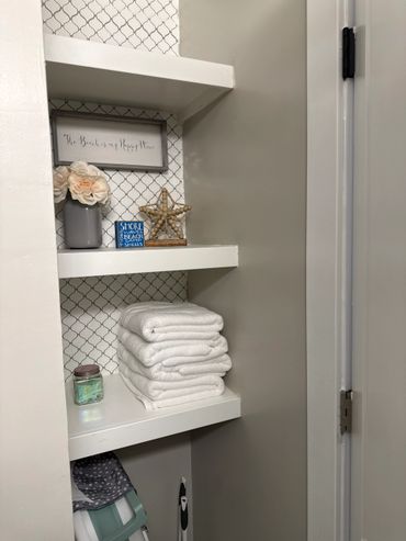 Cozy bathroom shelves with towels and beach-themed decor.