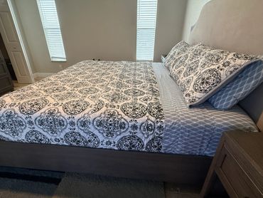 A neatly made bed with patterned bedding and pillows in a bright bedroom.