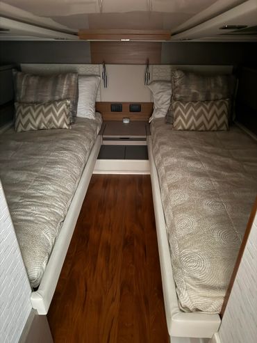 Compact twin beds with patterned bedding and pillows separated by a small nightstand in a cozy room.