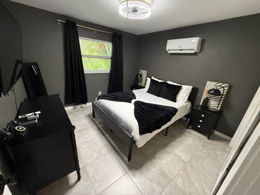 Modern bedroom with dark walls, black furniture, and white bedding.
