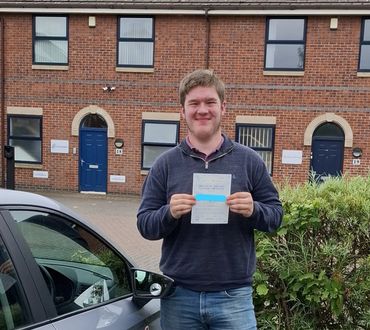 Man proudly holding a practical driving test pass certificate.