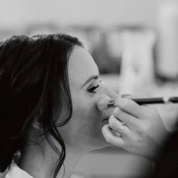 Woman having makeup applied with a brush, black and white.