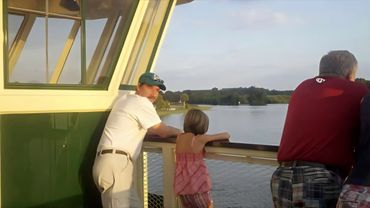 People enjoy scenic river views from a boat deck during a sunny day.
