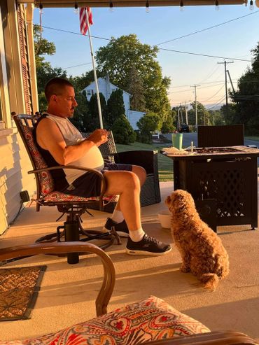 Man relaxing on a porch with his dog during golden hour.