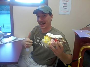 Man happily gives thumbs-up while holding a large ice cream sundae.