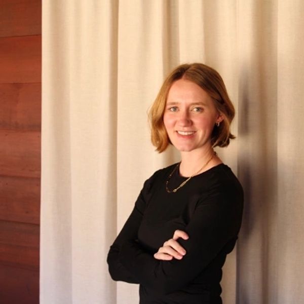Young woman with short hair smiling in black outfit.
