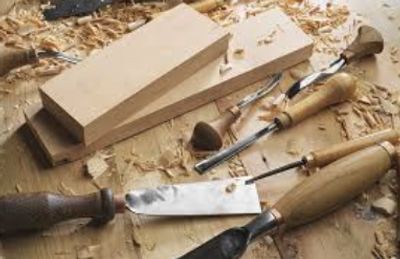 Woodworking tools and wood pieces on a workbench with wood shavings.