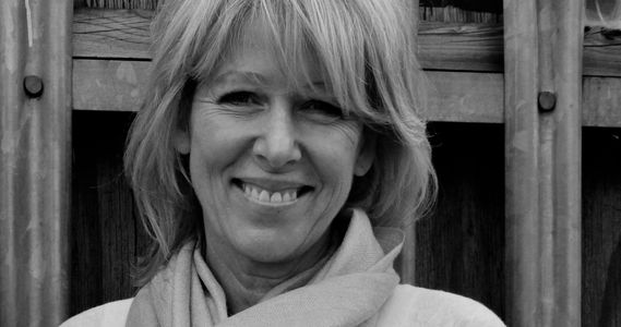 Black and white portrait of a smiling woman with a scarf.