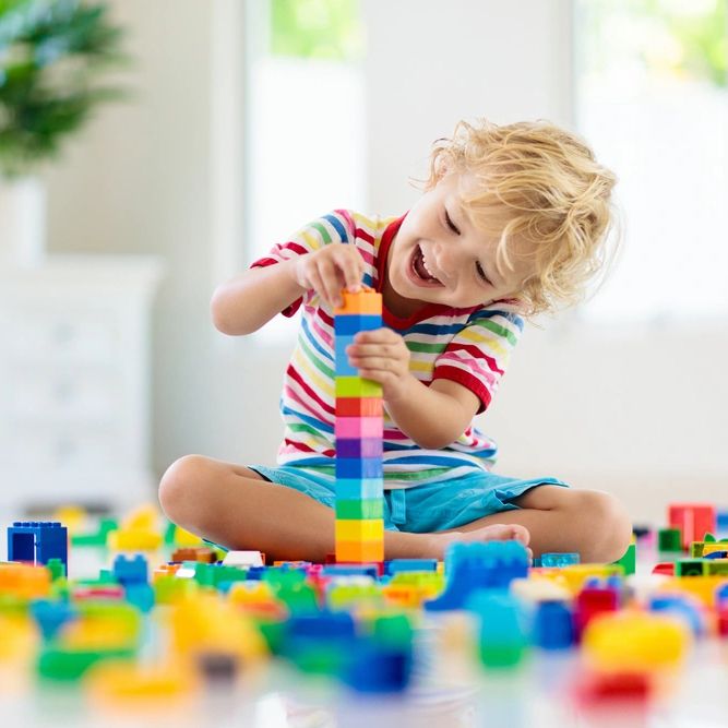 Child playing with colorful toy blocks. Little boy building tower at home or day care.