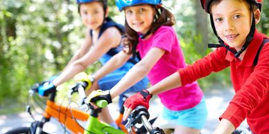 Three kids on bikes wearing helmets 