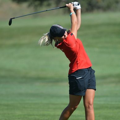 Young woman swinging a golf club.