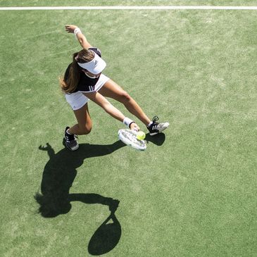 Girl playing tennis on grass tennis court.