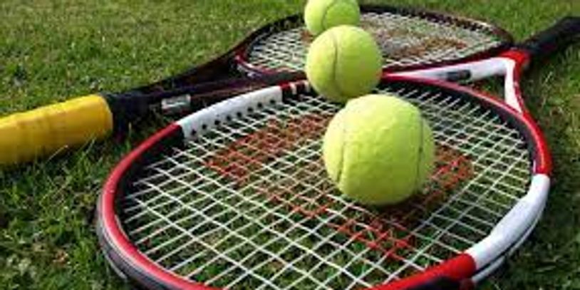 Three tennis balls on top of two tennis racquets on grass.