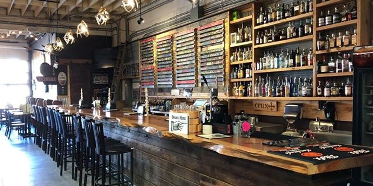 Rustic bar interior with wooden stools and a wide selection of drinks.
