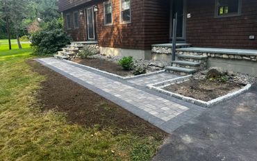Newly installed stone walkway leading to a house with brown siding.