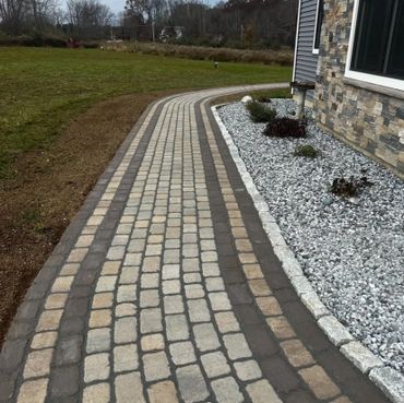 Curved stone pathway beside a house with a rock garden.