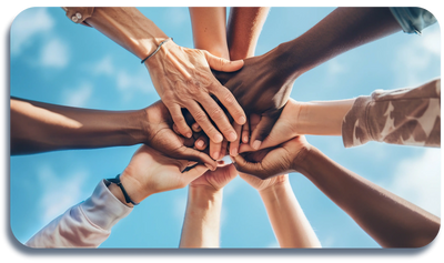 Diverse hands stacked together against a blue sky, symbolizing unity and teamwork.