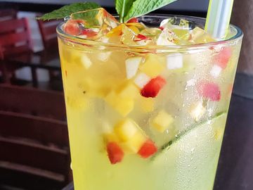 Refreshing iced fruit drink garnished with mint leaves and colorful fruit cubes.