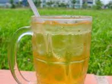 A refreshing iced beverage in a glass mug with a straw outdoors.
