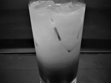 A glass of iced Thai tea with milk, showing distinct layers.