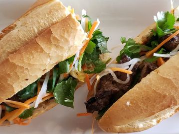 Two Vietnamese banh mi sandwiches on a white plate.