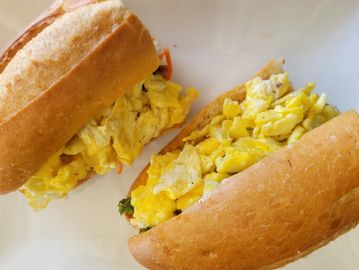 Two sandwiches filled with scrambled eggs on a white plate.