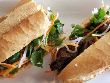 Two Vietnamese banh mi sandwiches on a white plate.