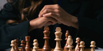 closeup shot of chess board with a women beside it.