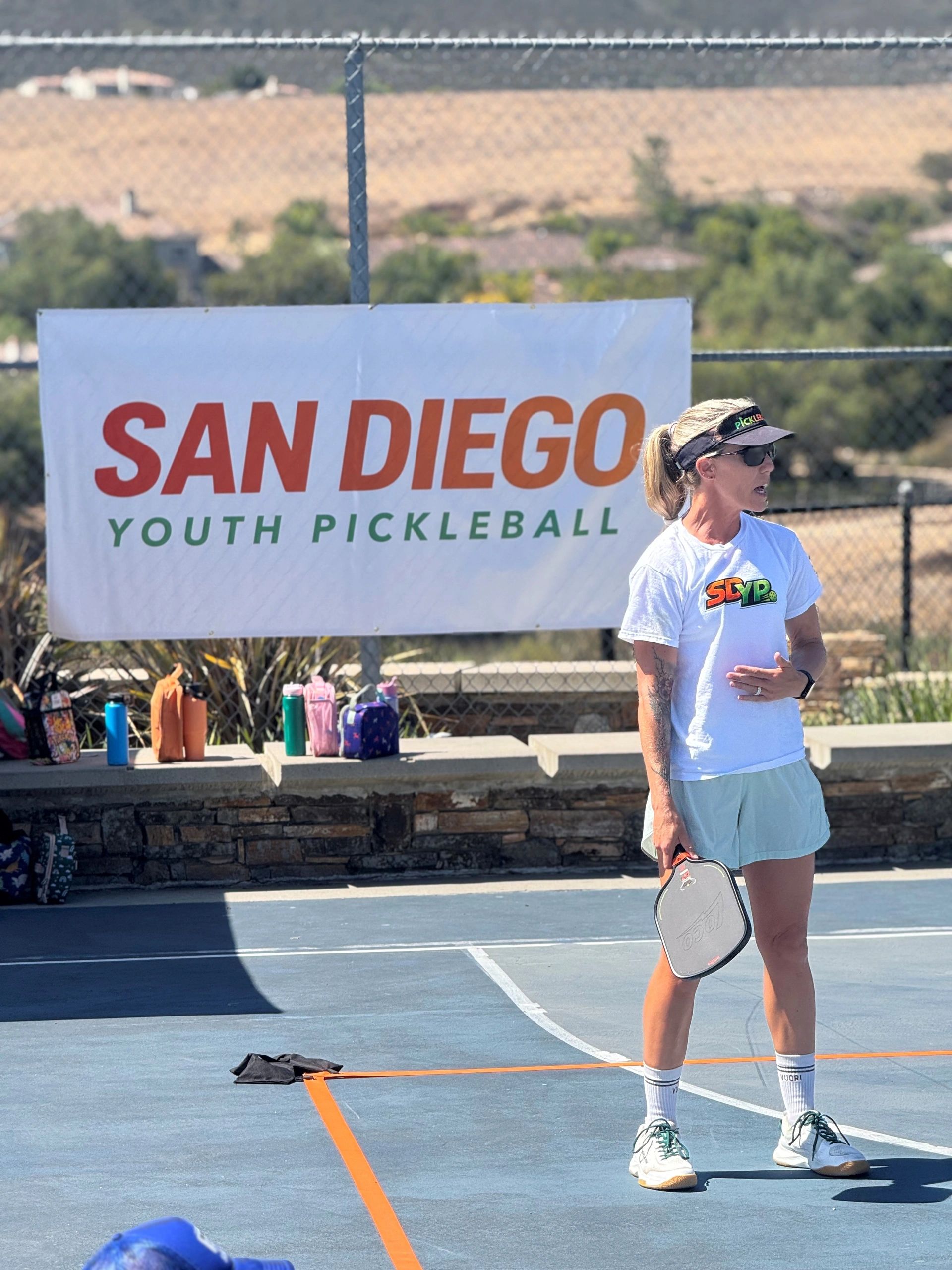Woman holding a pickleball paddle at a San Diego youth pickleball event.