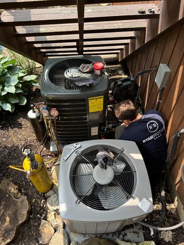 Technician repairing HVAC units outside a house.