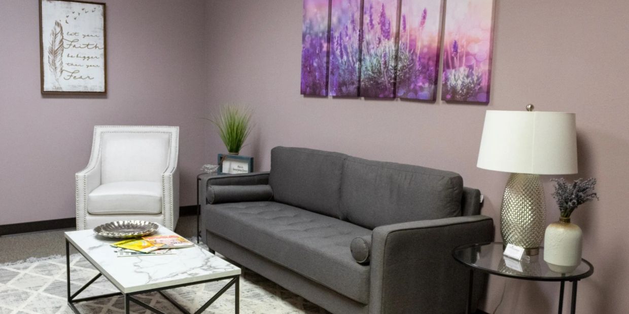 Cozy living room with gray sofa, white armchair, and purple floral wall art.