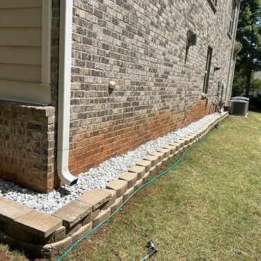 Clean side-yard landscaping with fresh grass, decorative rock bed, trimmed edges, and low-maintenance curb appeal.