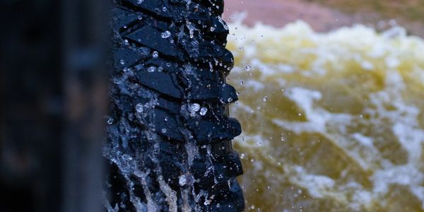 Close-up of a vehicle tire splashing water during an off-road adventure.