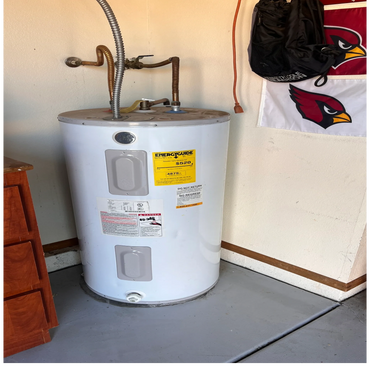 A white water heater with pipes in a garage corner.