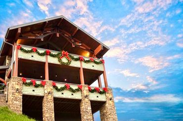 Rustic house decorated with Christmas wreaths and garlands against a vibrant sky.