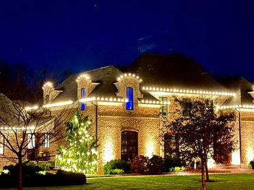 Elegant brick house illuminated with warm lights at night.