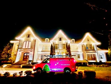 A large house decorated with bright Christmas lights at night.