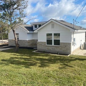 Single-story white house with stone accents and a green lawn under blue sky.