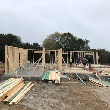 Early-stage wooden framing of a building under construction on a cloudy day.