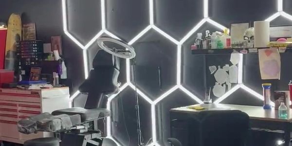 A modern tattoo studio with illuminated honeycomb wall lights and tattoo equipment.