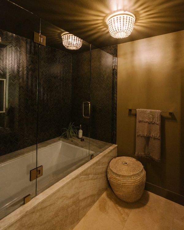 Cozy bathroom with a glass shower, basket, and warm lighting.