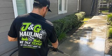 Person power washing a sidewalk beside a building.