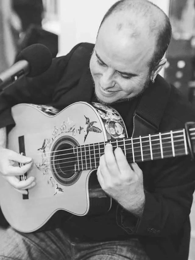 Man playing a decorated acoustic guitar.