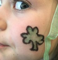 Young person's profile with eye on camera and shamrock face paint on cheed