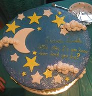 Round cake, decorated with dark blue fondant, with yellow and white fondant stars moon and clouds