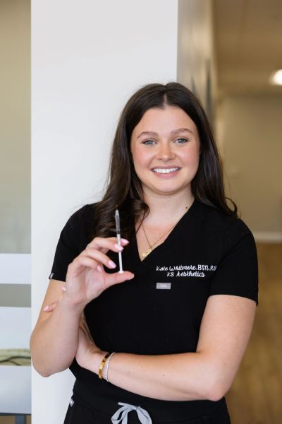 Smiling healthcare professional holding a syringe, ready for an aesthetic procedure.