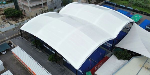 Aerial view of a covered sports court with adjacent buildings and greenery.