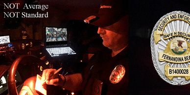 Security officer working at night with multiple monitors and badge.